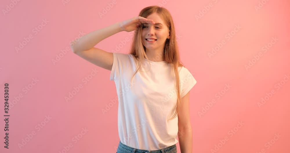 The girl looks forward, holding her hand above her head , on a pink background The girl looks forward, holding her hand above her head , on a pink background