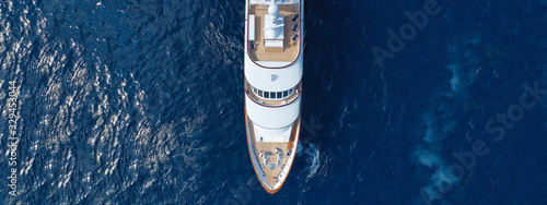 Aerial drone ultra wide top down photo of luxury yacht with wooden deck docked in Aegean island with deep blue sea, Greece