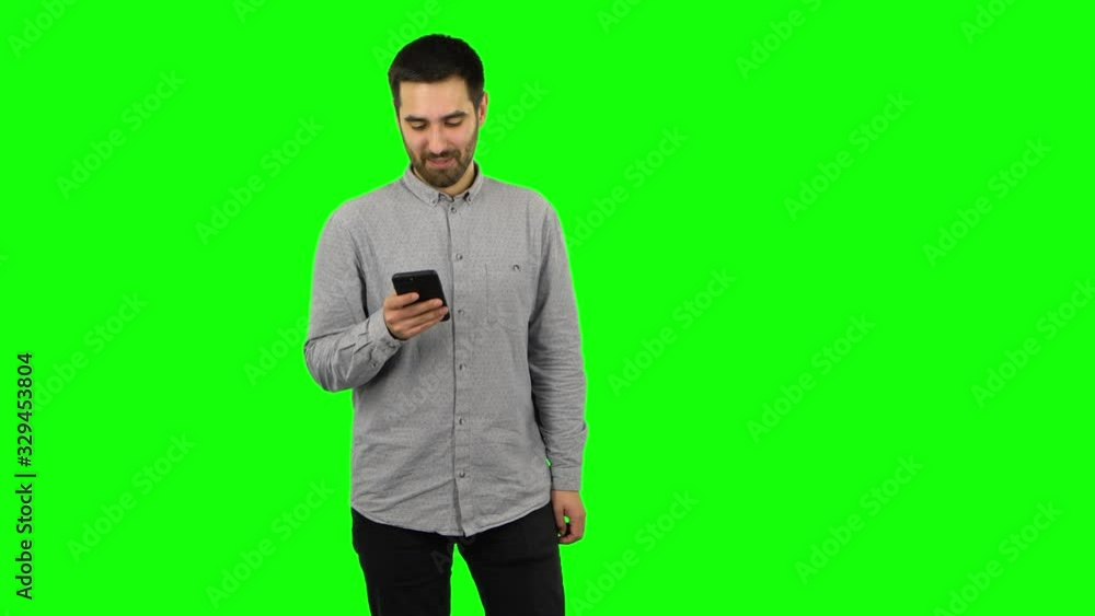 Brunette guy is texting on his phone and smiling. Green screen Brunette guy is texting on his phone and smiling. Green screen
