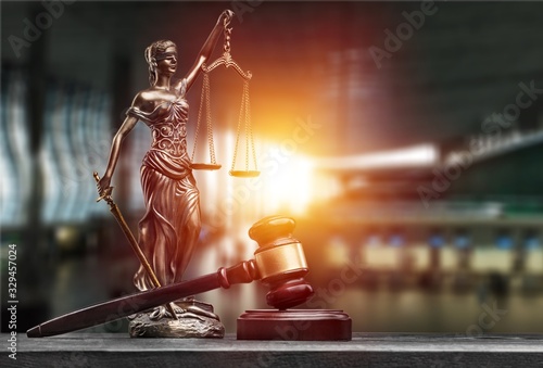 Statue of the lady of justice with scales and gavel on the desk