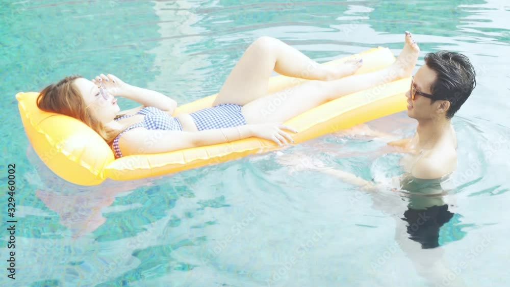Happy young couple in swimwear relaxing on the pool with float mattress. Shot in 4k resolution Happy young couple in swimwear relaxing on the pool with float mattress. Shot in 4k resolution