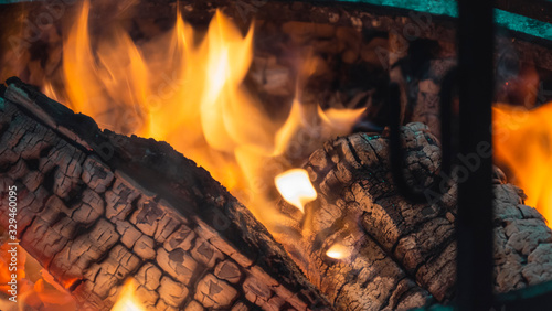 Burning Fire.Closeup. Bonfire, burning trees logs. Warm, cozy burning fire in a brick fireplace. Red, orange fire flame and smoke.Template.Place for text.