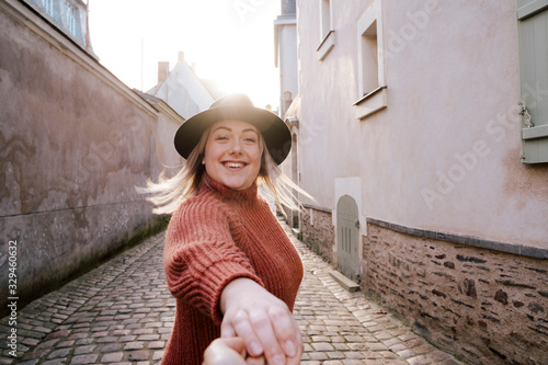 Beautiful real french woman holding the hand of her partner. Engaged female traveling and sightseeing in the medieval city of Angers  France. European destination. Travel and holidays concept.