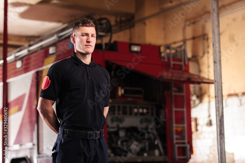 Professional fireman portrait. Firefighter wearing shirt uniform and fire truck in the background.