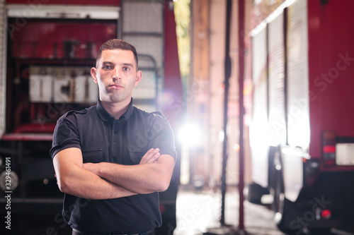 Professional fireman portrait. Firefighter wearing shirt uniform and fire truck in the background.