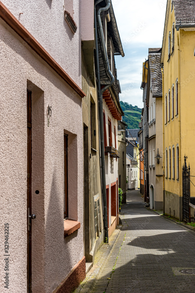 Fototapeta premium Germany, Rhine Romantic Cruise, Golden Lane, a person walking down a sidewalk in front of a brick building with Golden Lane in the background