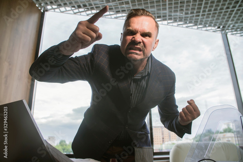 Fotografie angry boss screaming and waving his arms mad at the office