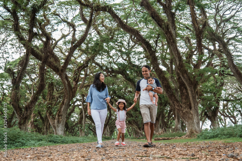 Obraz premium Asian families enjoy holidays together, father, mother and two children walking in the park