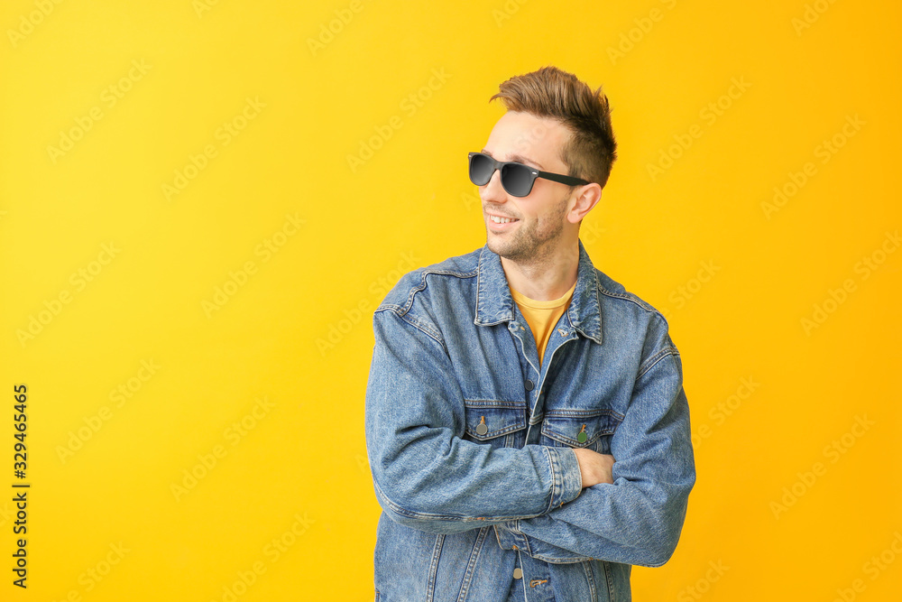 Fototapeta premium Young man with stylish sunglasses on color background