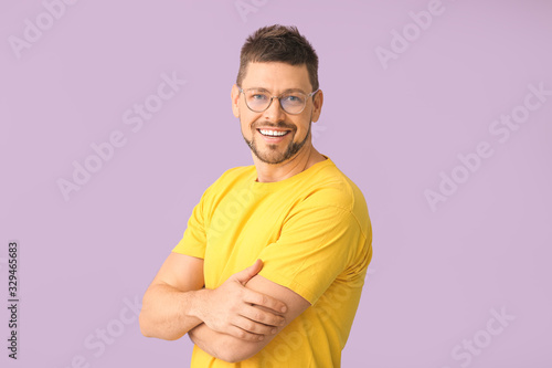 Handsome man with glasses on color background