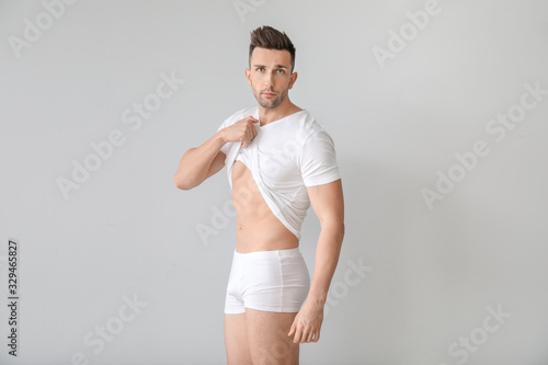 Handsome man in underwear on light background