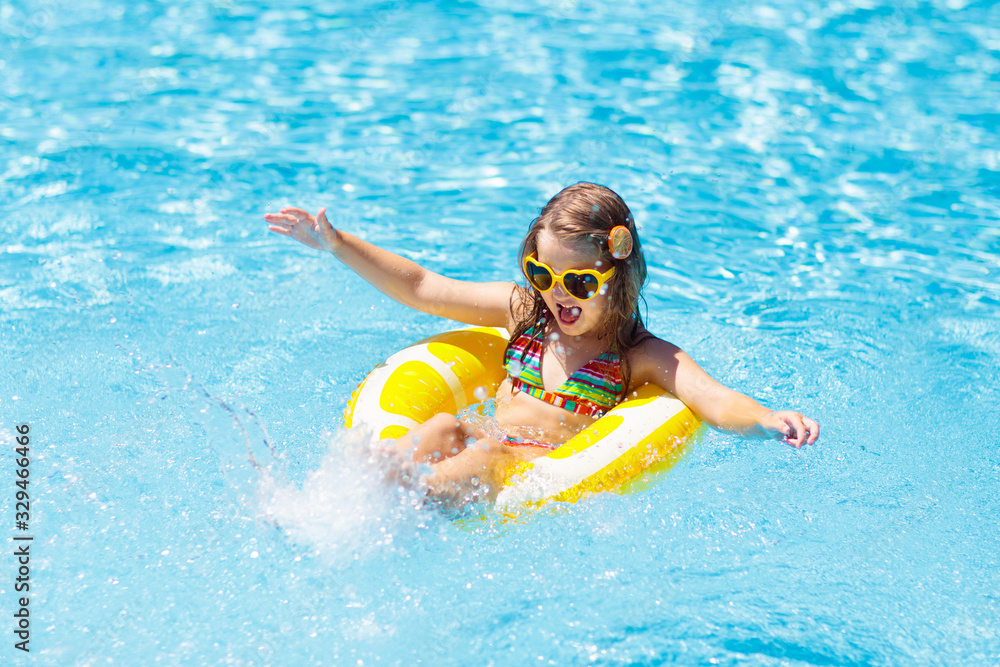 Child in swimming pool on ring toy. Kids swim.