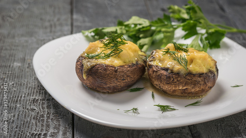 Mushrooms baked with cheese and herbs on a wooden table.