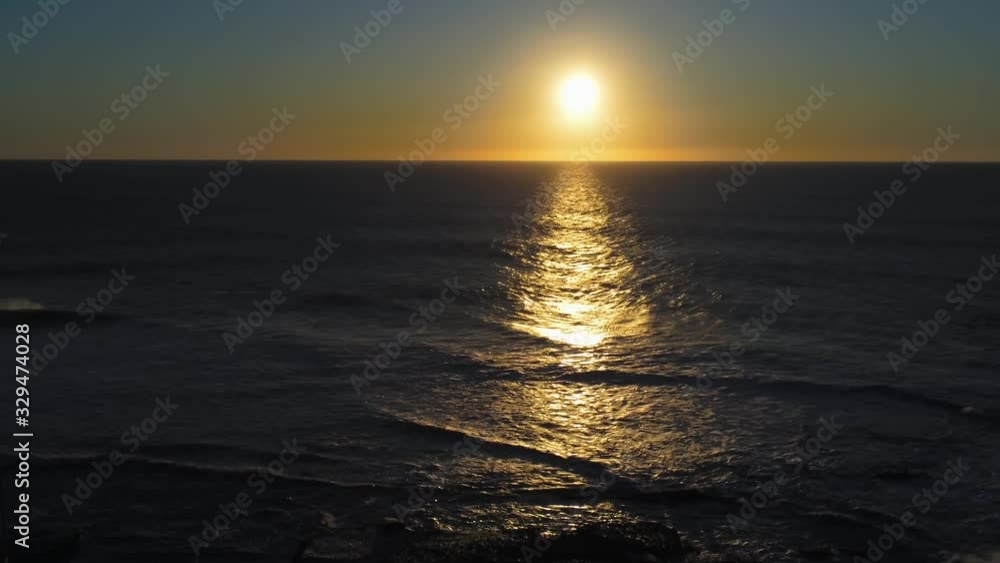 Aerial zoom out Sunset reflection on dark blue ocean, gentle waves wash ashore Aerial zoom out Sunset reflection on dark blue ocean, gentle waves wash ashore