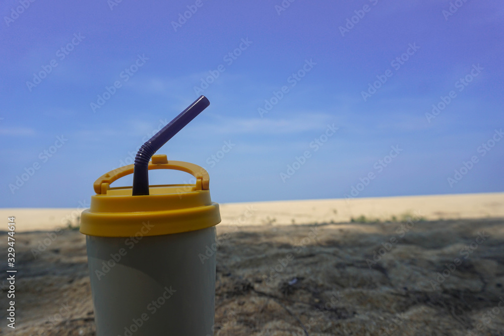 Stainless steel coffee mug on the sand behind the sea Stainless steel coffee mug on the sand behind the sea