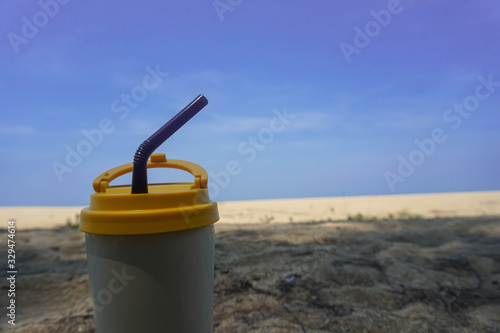 Stainless steel coffee mug on the sand behind the sea