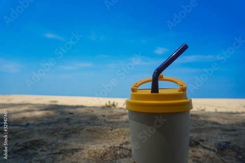 Stainless steel coffee mug on the sand behind the sea