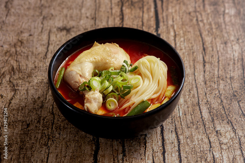 Spicy chicken noodle soup on wooden background 