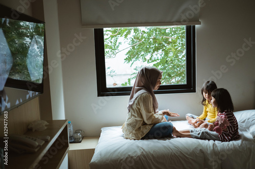 mother storytelling to her daughter on the bed play together