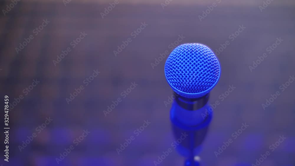 Microphone on stand close up, blurred empty theater audience. Arc shot Microphone on stand close up, blurred empty theater audience. Arc shot