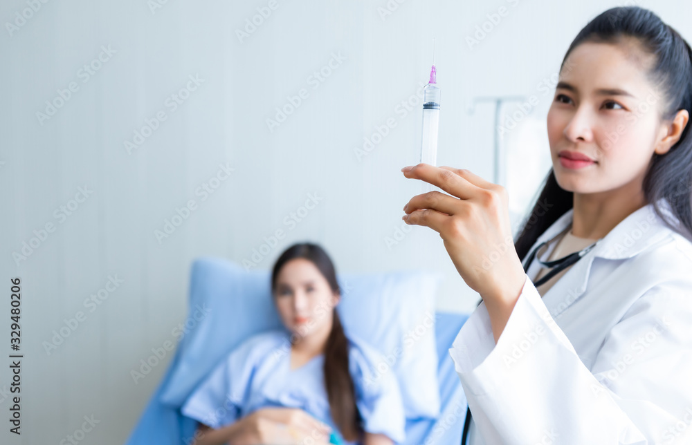 Asian young female doctor with syringe to Asian young female patient on Bed for better healing In the room hospital background. Asian young female doctor with syringe to Asian young female patient on Bed for better healing In the room hospital background.