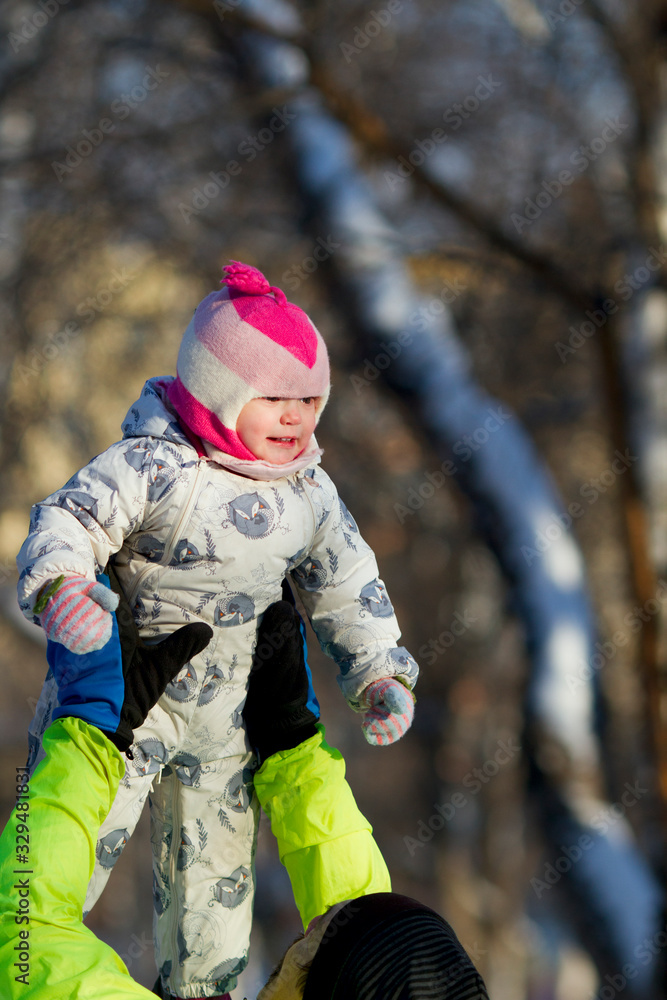 A man (father or grandfather) lifts a pretty baby up outdoors on a beautiful sunny winter day A man (father or grandfather) lifts a pretty baby up outdoors on a beautiful sunny winter day