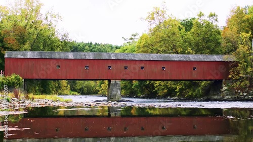 Red covered bridge in West Cornwall Connecticut reflected in Housatonic river profile wide II lower in frame photo