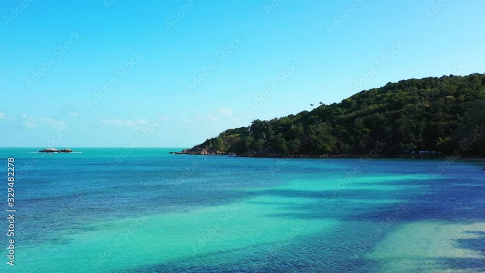 Vivid colors of peaceful seascape with blue azure sea washing rocky coastline of tropical island at sunrise Vivid colors of peaceful seascape with blue azure sea washing rocky coastline of tropical island at sunrise