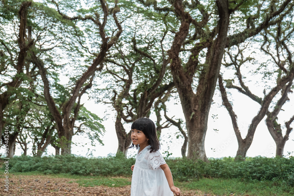 little girl running around the forrest wearing white dress little girl running around the forrest wearing white dress