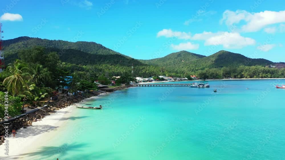 Calm azure lagoon washing exotic beach with palm trees and lush vegetation, anchored boats near wooden pier in Thailand Calm azure lagoon washing exotic beach with palm trees and lush vegetation, anchored boats near wooden pier in Thailand