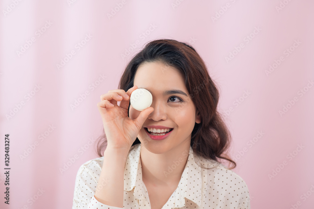 Funny young woman holding macaroons near eyes, against pink background Funny young woman holding macaroons near eyes, against pink background