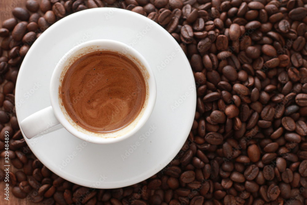 White cup of espresso coffee with saucer and dark roasted beans. Close object, top view. Coffee shop, fresh roast, drink concept White cup of espresso coffee with saucer and dark roasted beans. Close object, top view. Coffee shop, fresh roast, drink concept