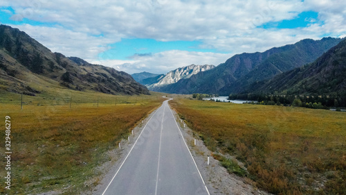 Smooth road going into the mountains into the distance. Mountain ranges are visible on the horizon. Landscape aerial view of a drone. Altai.