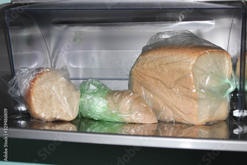 Different loaves of bread in a bread box and cellophane bags. photo