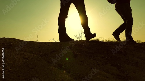 teamwork business people. feet of Free Travelers adventurers walk along top of mountain in rays of the beautiful sun. tourist travels in the mountains at sunset. striving for victory and success.