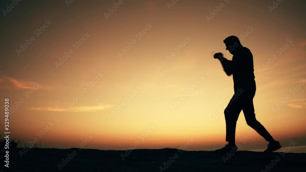 Man practices shadowboxing on a rock by the sea at dawn. Slow motion video. Man practices shadowboxing on a rock by the sea at dawn. Slow motion video.