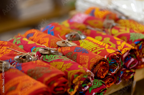 Traditional woven fabrics of various colors are displayed in a way rolled to attract tourists.
