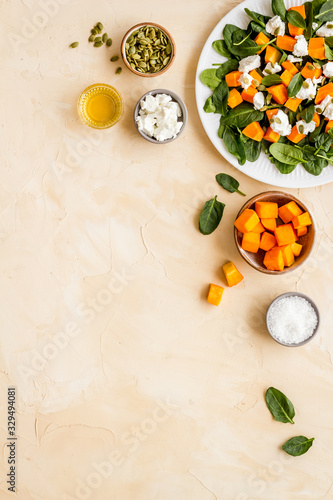 Salad with pumpkin and basil - near ingredients - on beige background top-down copy space