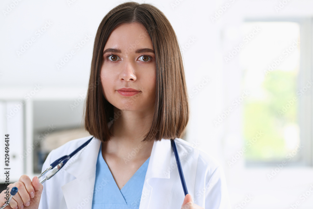 Beautiful smiling female doctor stand in office portrait. Physical and patient disease prevention exam er ward round 911 prescribe remedy healthy lifestyle consultant nurse profession concept Beautiful smiling female doctor stand in office portrait. Physical and patient disease prevention exam er ward round 911 prescribe remedy healthy lifestyle consultant nurse profession concept