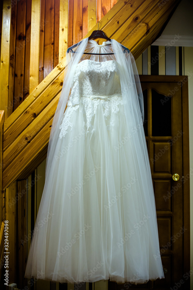 The bride's white dress hangs on a hanger