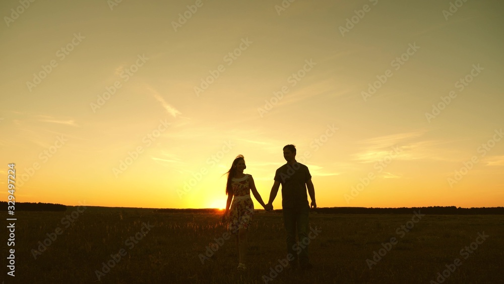 beautiful girl and guy go hand in hand in rays of sun in spring. happy married couple. happy family concept. young couple in love walks and listens to music on a smartphone.