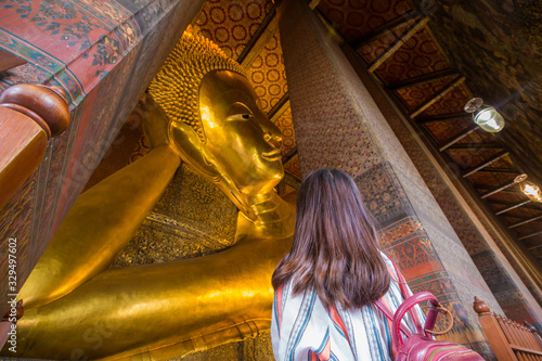 Fotografie Asian cute women travel in golden reclining buddha statue indoor temple pagoda