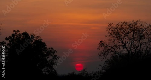 timelapse of red sun goes down behind the light clouds
