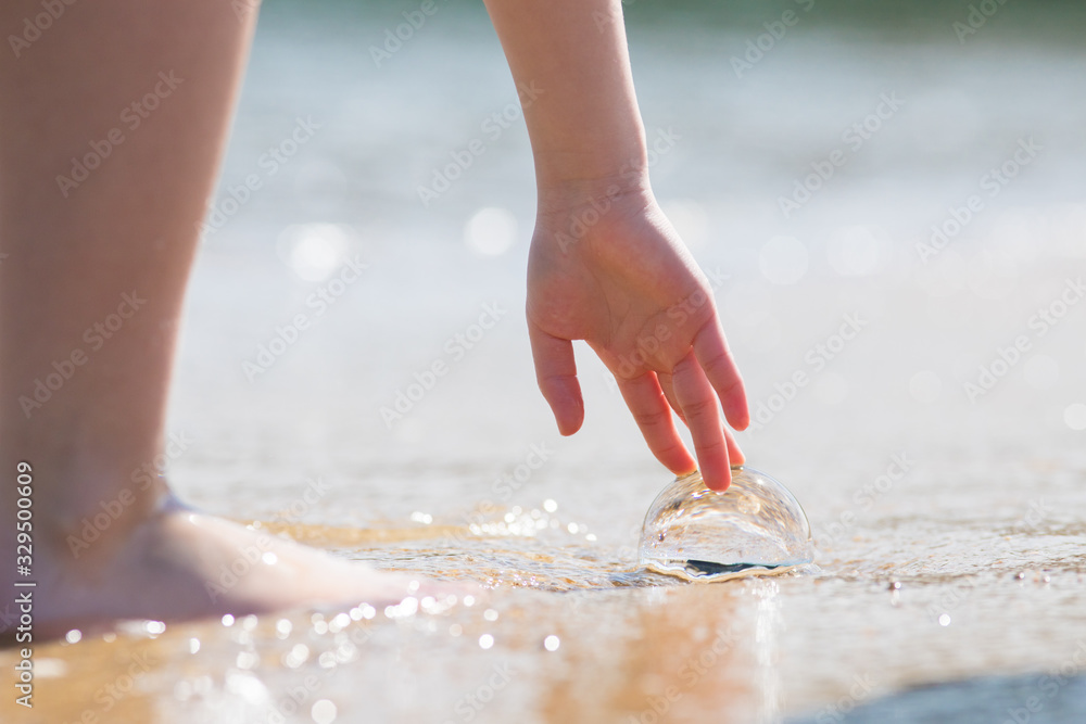 夏の海の砂浜に遊んでいる子供と透明な水晶ガラスボール
