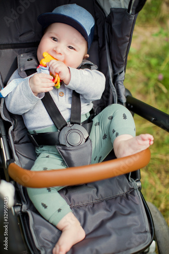 Little boy sitting in his stroller and play with toys