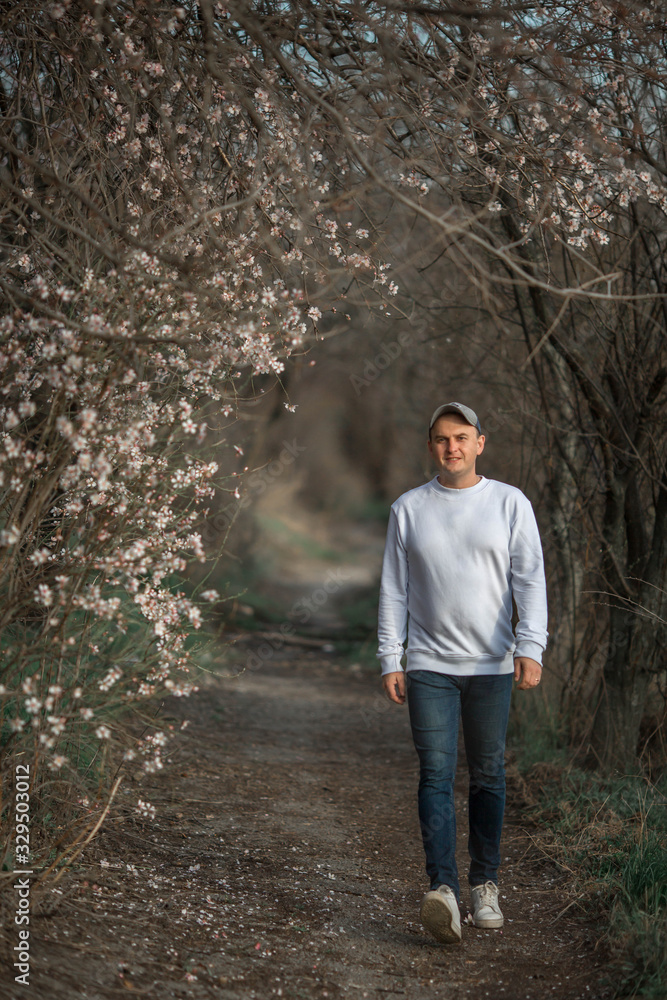 A guy in white pay is walking along a path under flowering almonds. A guy in white pay is walking along a path under flowering almonds.