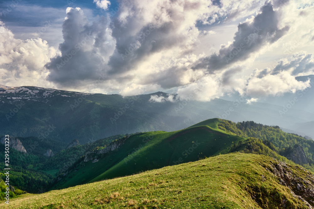 Fototapeta premium sun spots on meadow landscape with clouds. The formation and movement of clouds over the summer slopes of Adygea, Bolshoy Tkhach and the Caucasus Mountains 