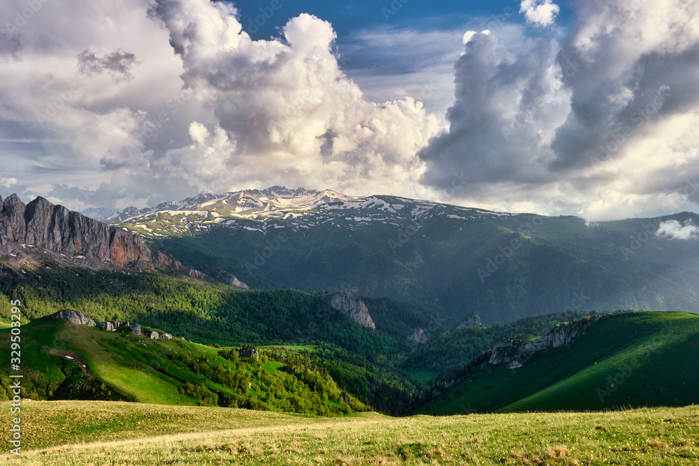 sun spots on meadow landscape with clouds. The formation and movement of clouds over the summer slopes of Adygea, Bolshoy Tkhach and the Caucasus Mountains 