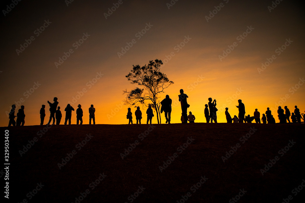 large number of people standing on hill top against beautiful sun rising sky