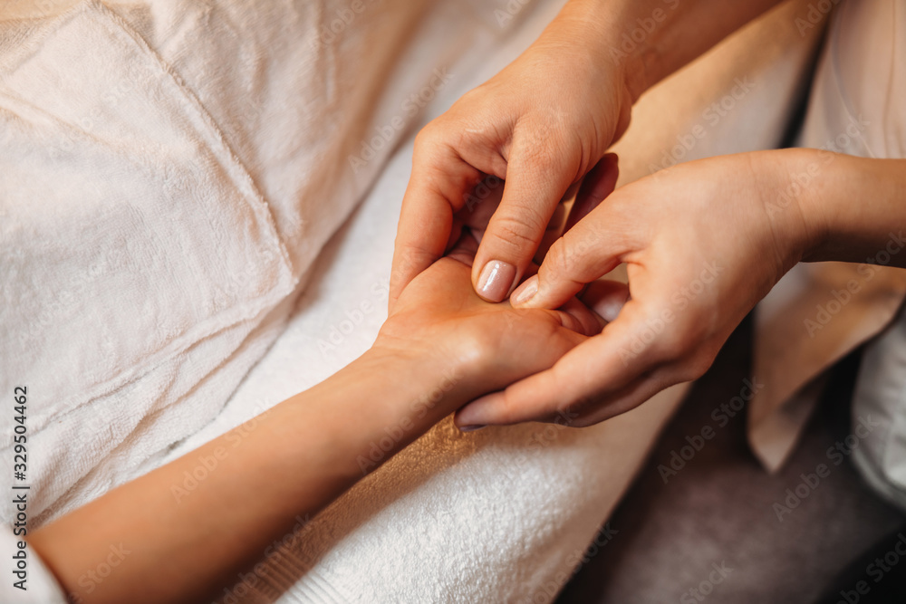 Experienced caucasian spa worker is massaging the client's hand during a spa session Experienced caucasian spa worker is massaging the client's hand during a spa session